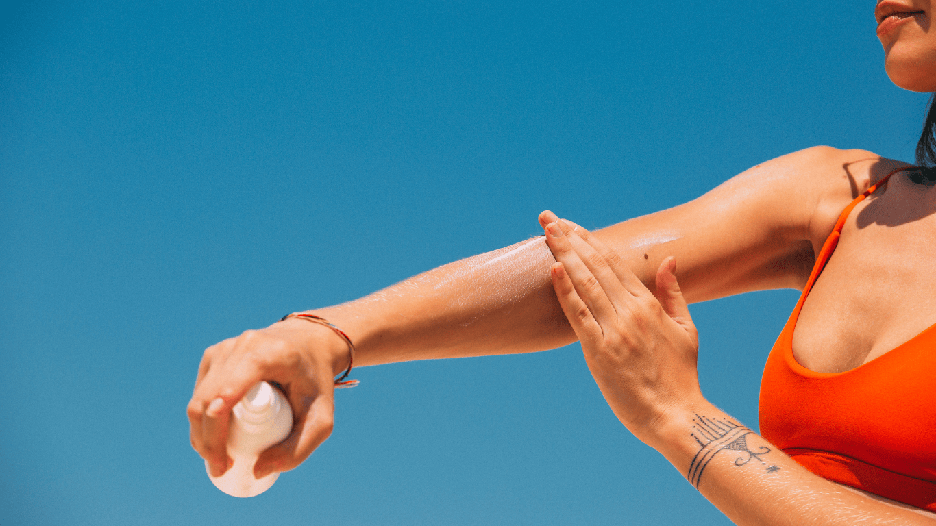 Primer plano de los brazos de una chica echándose crema de sol (fotoprotección) en el brazo